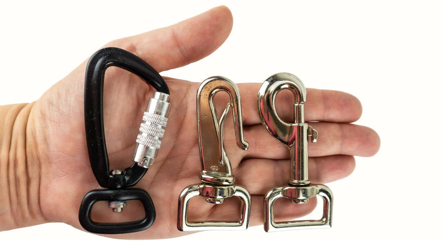 three different leash clips held in an adult hand for scale. 
