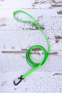 A 10-foot long neon green dog leash laid out on a white wood background.