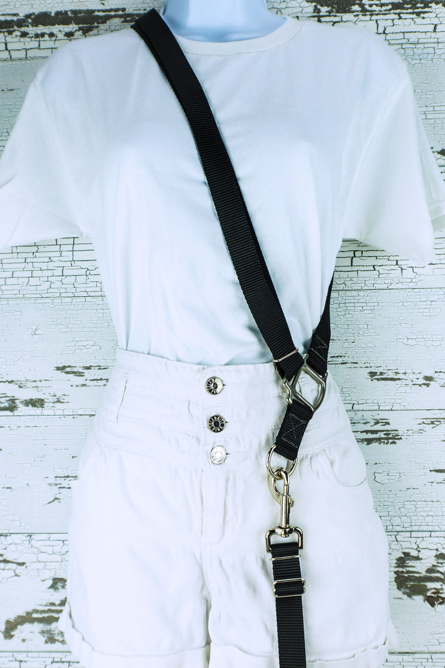 Black cross body strap shown on mannequin with clip on leash. 