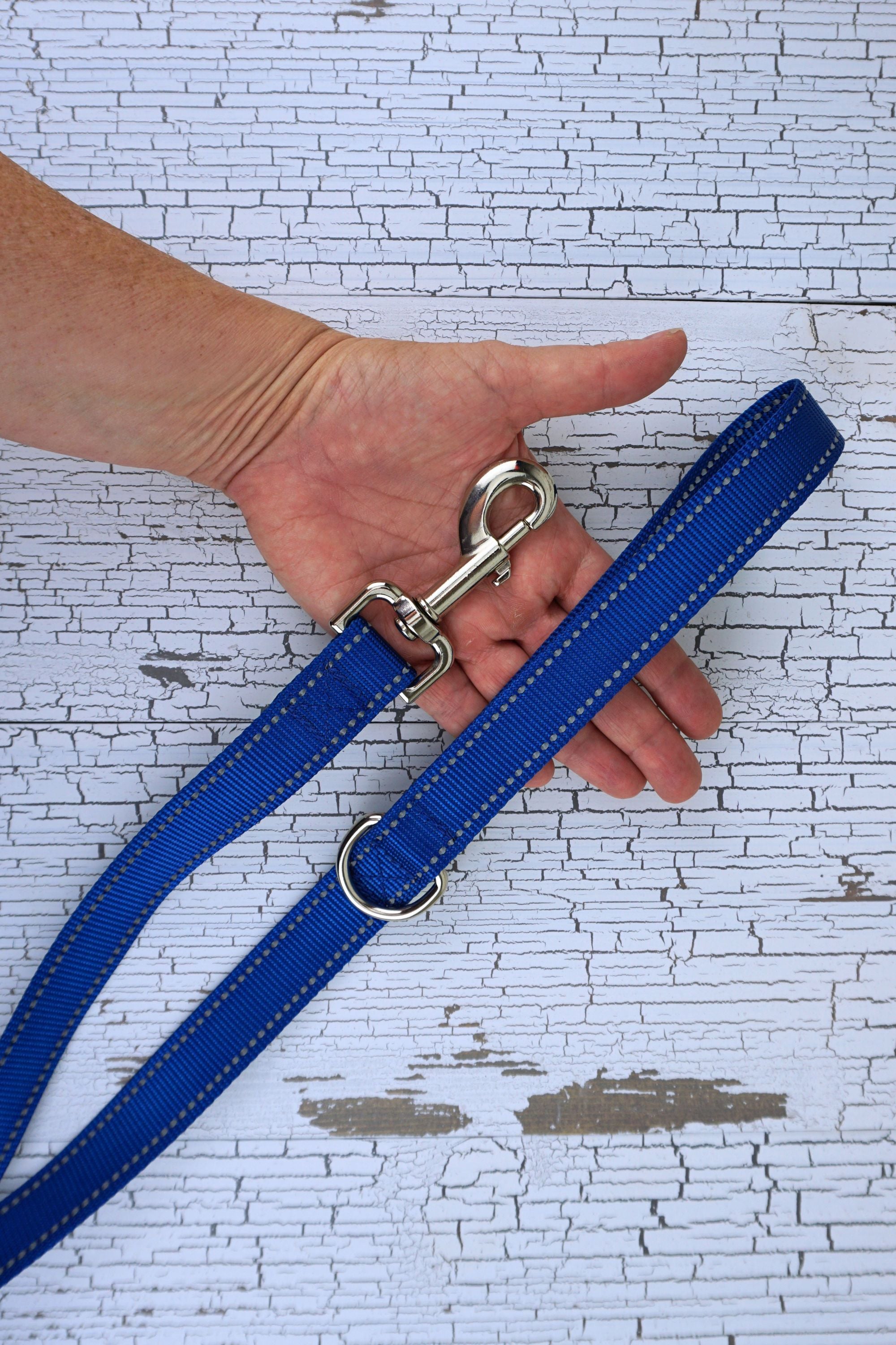 closeup of hardware on reflective loop handle leash. Includes swivel snap bolt or other hardware and a d ring next to the loop handle.