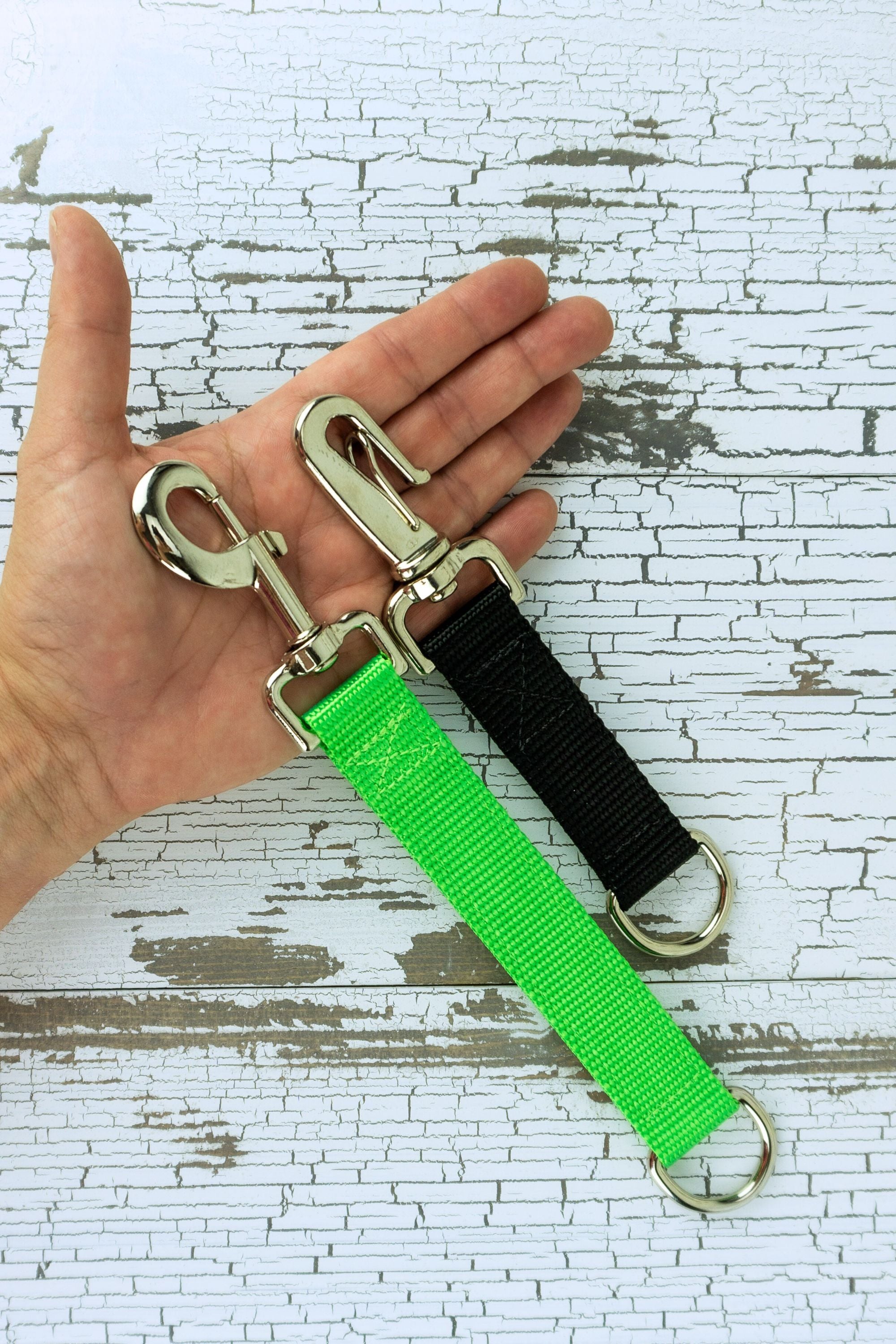 Training grab tabs shown in the palm of an adult hand for scale, this image highlights the gooseneck clip and the snap bolt.