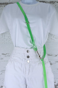 Three way adjustable and convertible leash for small dogs is shown in the cross body configuration, made in a neon green webbing.
