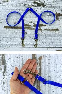 The adjustable leash coupler is shown in blue, with a closeup of the adjustable hardware and center o ring in the palm of an adult hand for scale.