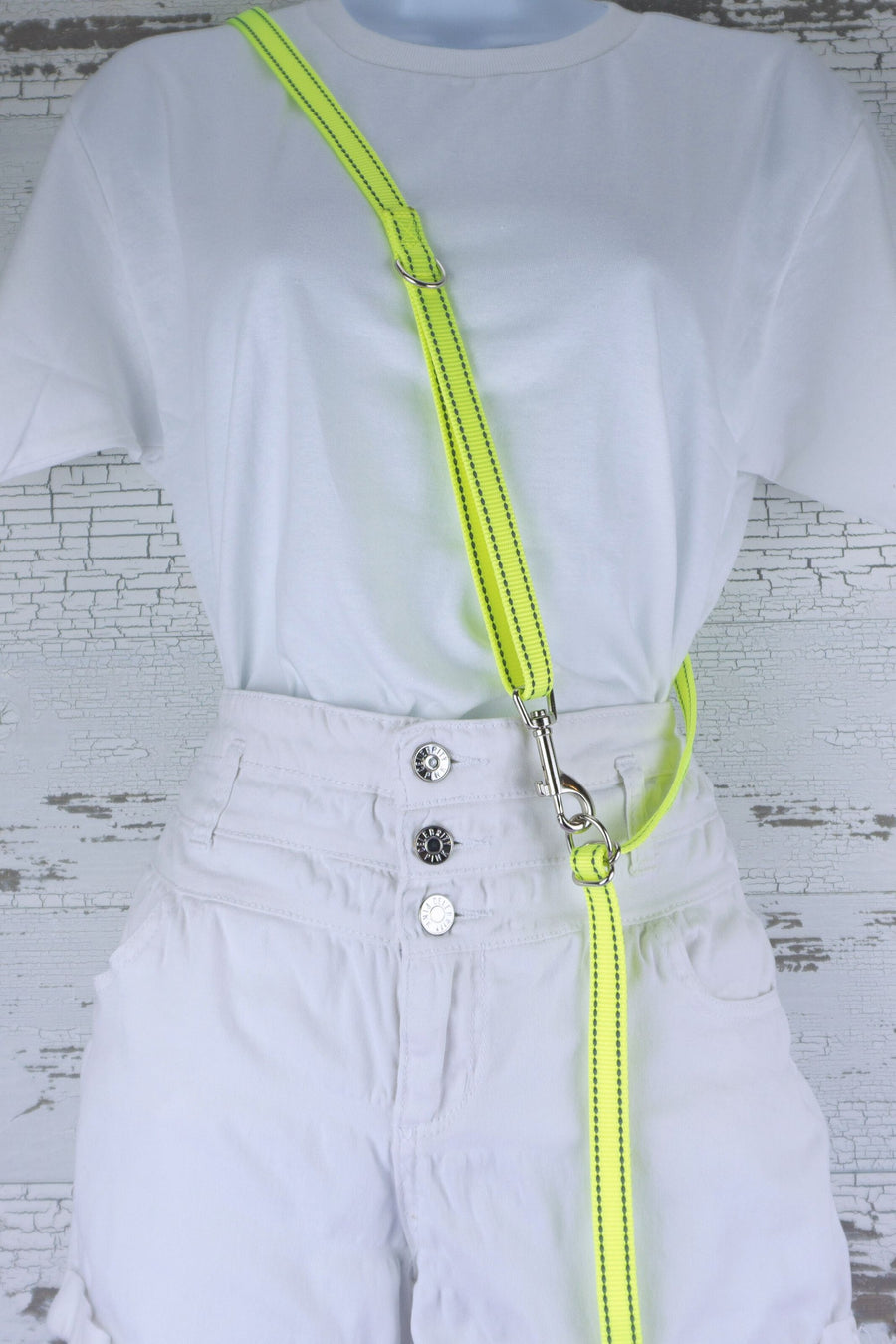 Three way adjustable and convertible leash for small dogs is shown in the cross body configuration, made in a reflective neon yellow webbing.
