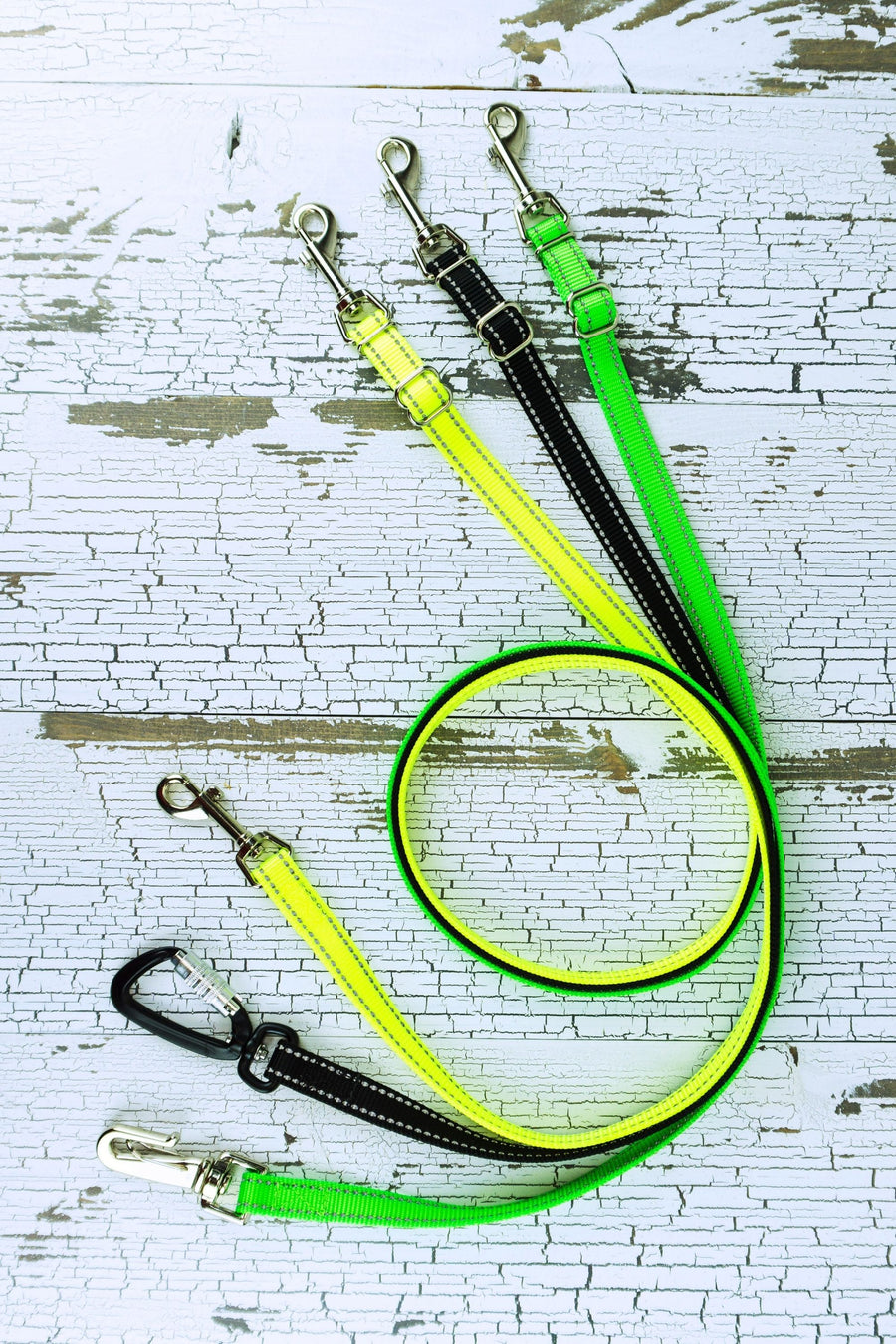 Reflective adjustable length hands free leashes for small dog shown in a swirl lay with neon yellow, black, and neon green leashes with a variety of hardware.