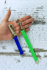 Training grab tabs shown in the palm of an adult hand for scale, this image highlights the gooseneck clip and the snap bolt.