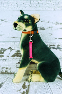 Neon pink medium duty training tab is shown clipped to the end of a dog mannequin's collar.