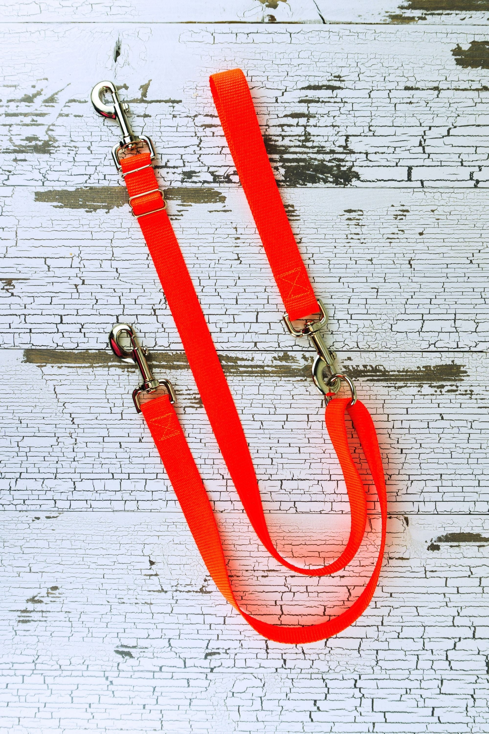 No pull adjustable leash in neon orange shown in flat lay with leash handle attached to floating d ring. Hardware selection is swivel snap bolts.