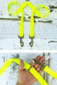 The fixed length leash coupler is shown with a hardware closeup in the palm of an adult hand.