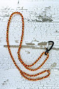 Orange blend color braided paracord leash in a flat lay, showing loop handles at each end with a auto locking carabiner at one end and a swivel snap bolt at the other end.